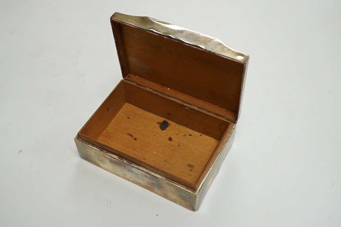 A George V part engine turned silver mounted cigarette box, by Clark & Sewell, with serpentine lid and engraved inscription, Birmingham, 1928, length 12.9cm.